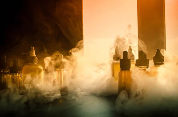 Vape concept. Smoke clouds and vape liquid bottles on window with sunlight on background. Light effects. Useful as background or vape advertisement or vape background. Close up