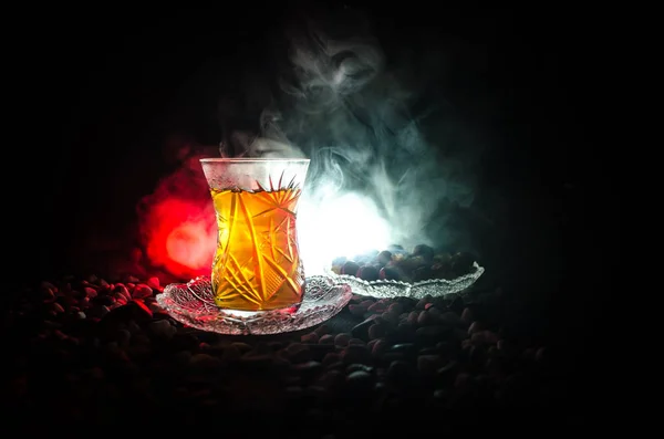 Türkischer Azerbaijan-Tee in traditionellem Glas und Kanne auf schwarzem Hintergrund mit Licht und Rauch. Armudu-Pokal — Stockfoto