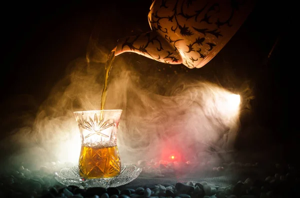 Té turco de Azerbaiyán en vidrio tradicional y olla sobre fondo negro con luces y humo. Copa tradicional Armudu — Foto de Stock