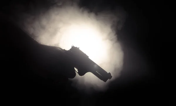 Pistola de mano masculina sobre fondo negro con luces traseras de color humo (amarillo anaranjado rojo blanco), concepto asesino de la mafia — Foto de Stock