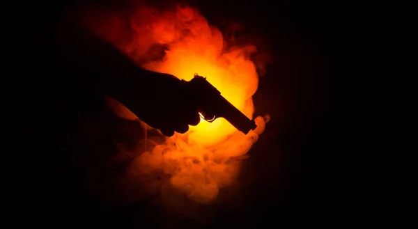 Pistola de mano masculina sobre fondo negro con luces traseras de color humo (amarillo anaranjado rojo blanco), concepto asesino de la mafia —  Fotos de Stock