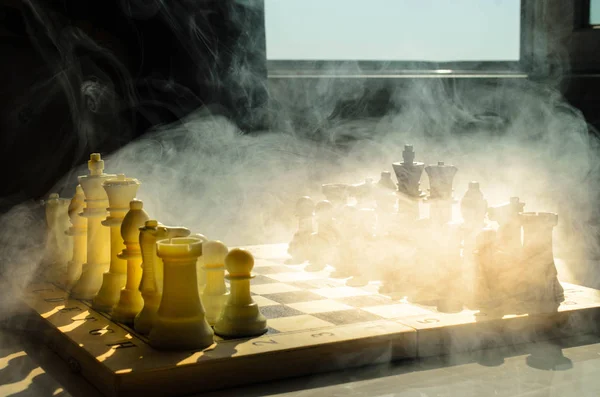 Jeu d'échiquier concept d'idées d'affaires et de la concurrence et des idées de stratégie concéder. Chess figures sur un fond sombre avec de la fumée et du brouillard. Concentration sélective. Main met figure à bord — Photo