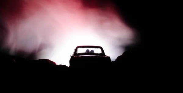 Silhouette de voiture avec couple à l'intérieur sur fond sombre avec des lumières et de la fumée. Scène romantique. Concept d'amour — Photo