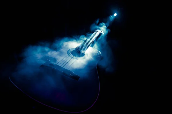 Conceito musical. Guitarra acústica isolada em fundo escuro sob feixe de luz com fumaça com espaço de cópia. Cordas de guitarra, de perto. Foco seletivo. Efeitos de fogo — Fotografia de Stock