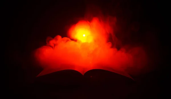 Abrir livro perto de lâmpada de mesa brilhante no fundo escuro, Lâmpada e livro aberto com fumaça no fundo. Surreal. — Fotografia de Stock