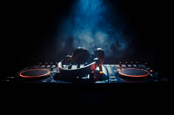 DJ Spinning, Mixing, e Scratching in a Night Club, Mãos de dj ajustam vários controles de pista no deck do dj, luzes estroboscópicas e nevoeiro, foco seletivo — Fotografia de Stock