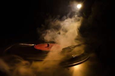Pikap vinil plak çalar. Retro ses ekipmanları için disk jokey. Dj mix ve müzik çalmak için ses teknolojisi. Yangın arka plan duman ile yanan karşı oynanan vinil kaydı. Vintage