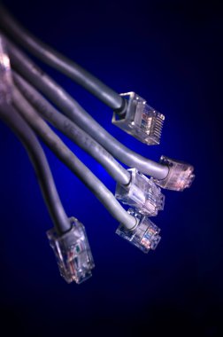 Ağ anahtarı ve ethernet kabloları, global iletişim sembolüdür. Işıklar ve duman ile koyu arka plan üzerinde renkli ağ kabloları. Seçici odak