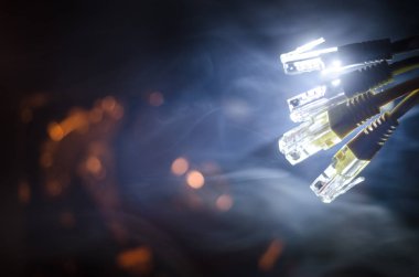 Ağ anahtarı ve ethernet kabloları, global iletişim sembolüdür. Işıklar ve duman ile koyu arka plan üzerinde renkli ağ kabloları. Seçici odak