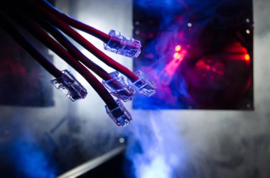 Ağ anahtarı ve ethernet kabloları, global iletişim sembolüdür. Işıklar ve duman ile koyu arka plan üzerinde renkli ağ kabloları. Seçici odak