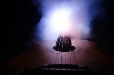 Müzik konsepti. Akustik gitar ile kopya alanı dumanla ışık demeti altında karanlık bir arka plan üzerinde izole. Gitar telleri, yakın çekim. Seçici odak. Yangın etkileri