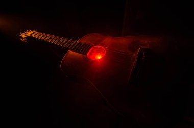 Müzik konsepti. Akustik gitar ile kopya alanı dumanla ışık demeti altında karanlık bir arka plan üzerinde izole. Gitar telleri, yakın çekim. Seçici odak. Yangın etkileri