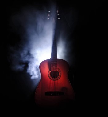 Müzik konsepti. Akustik gitar ile kopya alanı dumanla ışık demeti altında karanlık bir arka plan üzerinde izole. Gitar telleri, yakın çekim. Seçici odak. Yangın etkileri