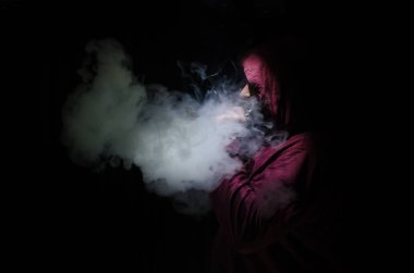 Bir mod tutarak Vaping adam. Buhar bulutu. Siyah arka plan. Vaping çok duman ile elektronik sigara