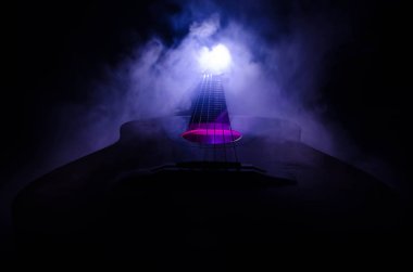 Müzik konsepti. Akustik gitar ile kopya alanı dumanla ışık demeti altında karanlık bir arka plan üzerinde izole. Gitar telleri, yakın çekim. Seçici odak. Yangın etkileri