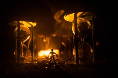 Zaman kavramı. Duman ile hourglasses ve karanlık bir arka plan ışıkları arasında duran bir adam silüeti.