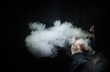 Bir mod tutarak Vaping adam. Buhar bulutu. Siyah arka plan. Vaping çok duman ile elektronik sigara