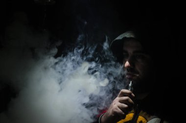 Bir mod tutarak Vaping adam. Buhar bulutu. Siyah arka plan. Vaping çok duman ile elektronik sigara