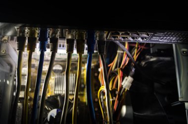 Ağ anahtarı ve ethernet kabloları, global iletişim sembolüdür. Işıklar ve duman ile koyu arka plan üzerinde renkli ağ kabloları. Seçici odak