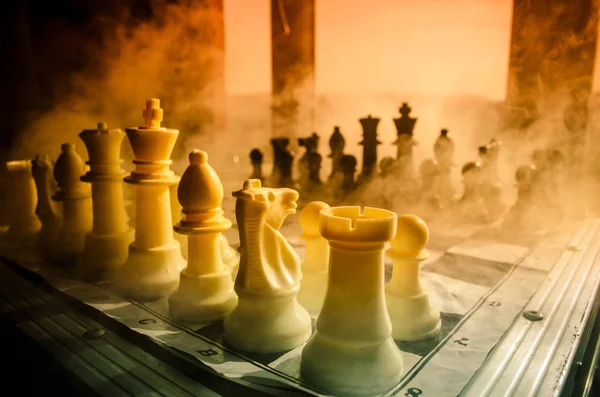 Jeu d'échiquier concept d'idées d'affaires et de la concurrence et des idées de stratégie concéder. Chiffres d'échecs sur fond sombre avec fumée et brouillard et fenêtre avec lumière du soleil . — Photo