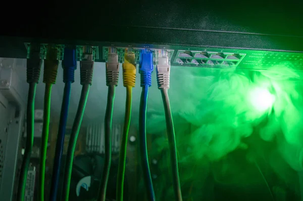 Network switch and ethernet cables, symbol of global communications. Colored network cables on dark background with lights and smoke. Selective focus