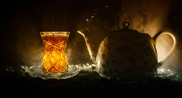 Té turco de Azerbaiyán en vidrio tradicional y olla sobre fondo negro con luces y humo. Copa tradicional Armudu — Foto de Stock