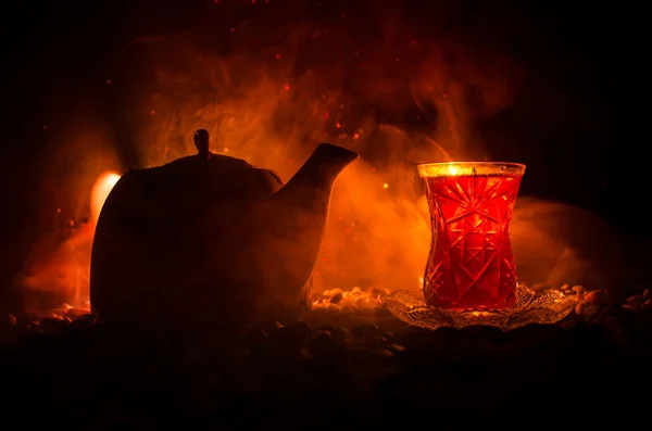 Té turco de Azerbaiyán en vidrio tradicional y olla sobre fondo negro con luces y humo. Copa tradicional Armudu — Foto de Stock