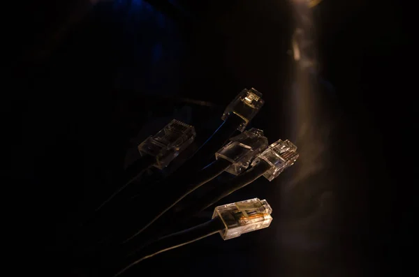 Tombol jaringan dan kabel ethernet, simbol komunikasi global. Kabel jaringan berwarna di latar belakang gelap dengan lampu dan asap. Fokus selektif — Stok Foto