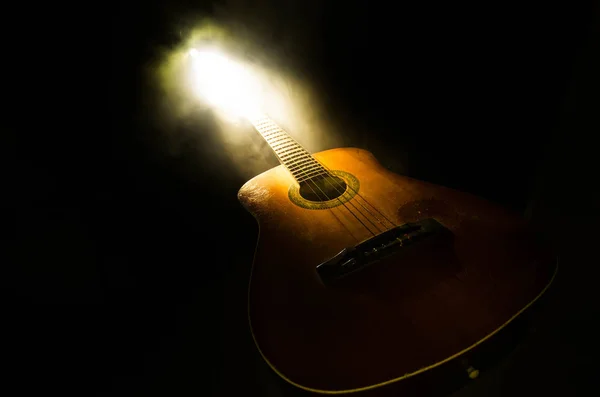 Музична концепція. Акустична гітара ізольована на темному фоні під промінь світла з димом з копіювальним простором. Гітарні струни, крупним планом. Вибірковий фокус. Пожежні ефекти — стокове фото