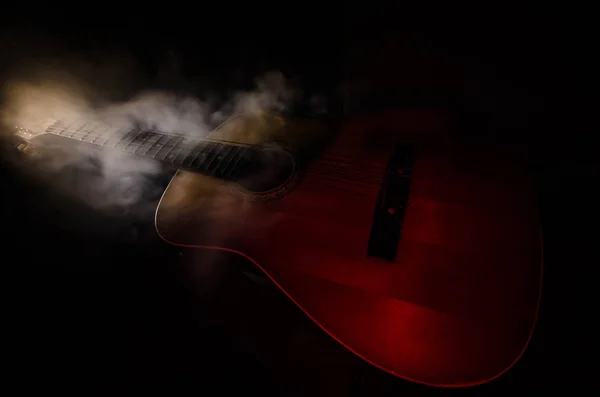 Music concept. Acoustic guitar isolated on a dark background under beam of light with smoke with copy space. Guitar Strings, close up. Selective focus. Fire effects