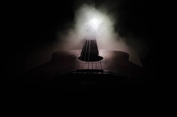 Концепция музыки. Акустическая гитара изолирована на тёмном фоне под лучом света с дымом с копировальным пространством. Гитарные струны, закройте. Выборочный фокус. Огненные эффекты — стоковое фото