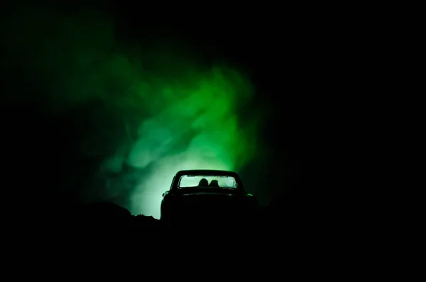 silhouette of car with couple inside on dark background with lights and smoke. Romantic scene. Love concept