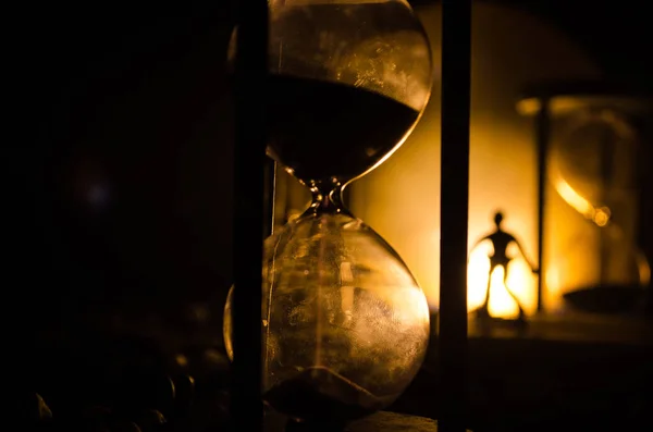 Concepto de tiempo. Silueta de un hombre parado entre clepsidras con humo y luces sobre un fondo oscuro . —  Fotos de Stock