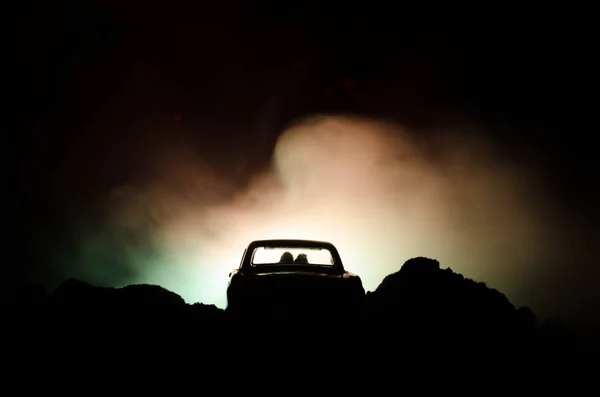 Silhueta de carro com casal dentro no fundo escuro com luzes e fumaça. Cena romântica. Conceito de amor — Fotografia de Stock