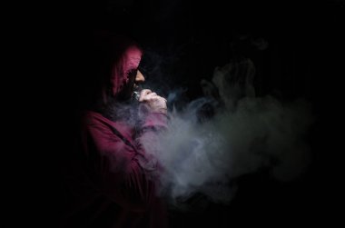Bir mod tutarak Vaping adam. Buhar bulutu. Siyah arka plan. Vaping çok duman ile elektronik sigara