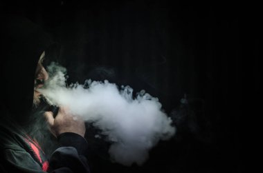 Bir mod tutarak Vaping adam. Buhar bulutu. Siyah arka plan. Vaping çok duman ile elektronik sigara