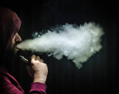 Bir mod tutarak Vaping adam. Buhar bulutu. Siyah arka plan. Vaping çok duman ile elektronik sigara