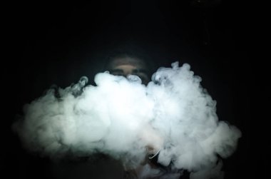Bir mod tutarak Vaping adam. Buhar bulutu. Siyah arka plan. Vaping çok duman ile elektronik sigara
