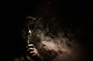 Bir mod tutarak Vaping adam. Buhar bulutu. Siyah arka plan. Vaping çok duman ile elektronik sigara