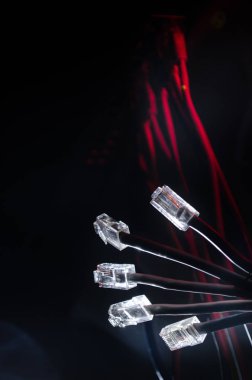 Ağ anahtarı ve ethernet kabloları, global iletişim sembolüdür. Işıklar ve duman ile koyu arka plan üzerinde renkli ağ kabloları. Seçici odak