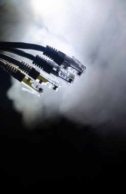 Ağ anahtarı ve ethernet kabloları, global iletişim sembolüdür. Işıklar ve duman ile koyu arka plan üzerinde renkli ağ kabloları. Seçici odak