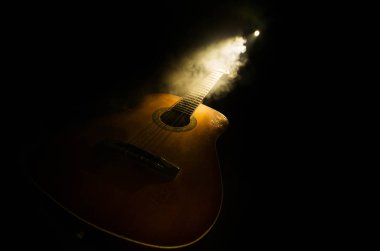 Müzik konsepti. Akustik gitar ile kopya alanı dumanla ışık demeti altında karanlık bir arka plan üzerinde izole. Gitar telleri, yakın çekim. Seçici odak. Yangın etkileri