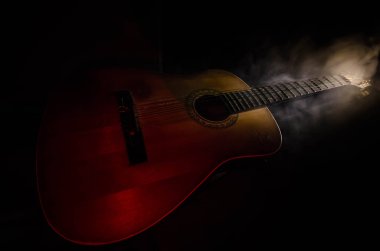 Müzik konsepti. Akustik gitar ile kopya alanı dumanla ışık demeti altında karanlık bir arka plan üzerinde izole. Gitar telleri, yakın çekim. Seçici odak. Yangın etkileri