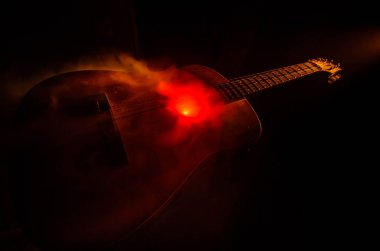 Müzik konsepti. Akustik gitar ile kopya alanı dumanla ışık demeti altında karanlık bir arka plan üzerinde izole. Gitar telleri, yakın çekim. Seçici odak. Yangın etkileri
