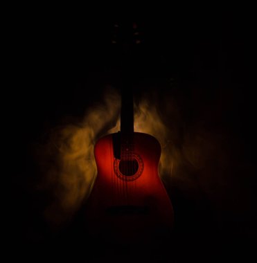 Müzik konsepti. Akustik gitar ile kopya alanı dumanla ışık demeti altında karanlık bir arka plan üzerinde izole. Gitar telleri, yakın çekim. Seçici odak. Yangın etkileri