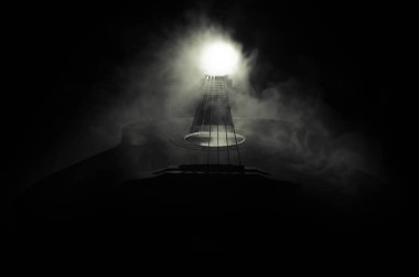 Müzik konsepti. Akustik gitar ile kopya alanı dumanla ışık demeti altında karanlık bir arka plan üzerinde izole. Gitar telleri, yakın çekim. Seçici odak. Yangın etkileri