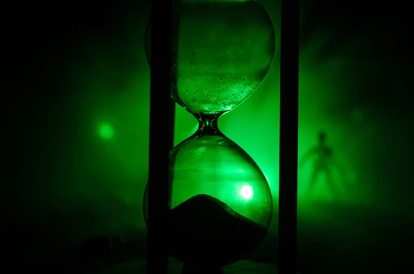 Time concept. Silhouette of a man standing between hourglasses with smoke and lights on a dark background. — Stock Photo, Image