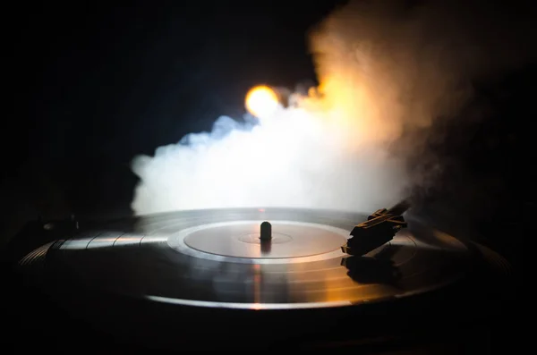 Turntable vinyl record player. Retro audio equipment for disc jockey. Sound technology for DJ to mix & play music. Vinyl record being played against burning fire background with smoke. Vintage — Stock Photo, Image