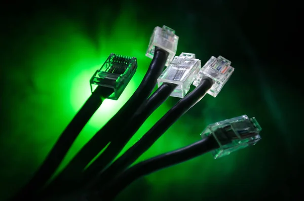 Interruptor de rede e cabos ethernet, símbolo de comunicações globais. Cabos de rede coloridos sobre fundo escuro com luzes e fumaça. Foco seletivo — Fotografia de Stock