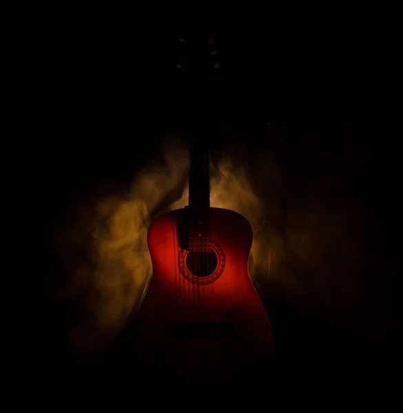 Music concept. Acoustic guitar isolated on a dark background under beam of light with smoke with copy space. Guitar Strings, close up. Selective focus. Fire effects — Stock Photo, Image